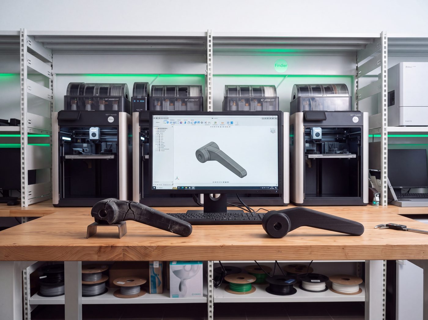 Prasklá původní páka, její CAD model na monitoru a nově vyrobený náhradní díl